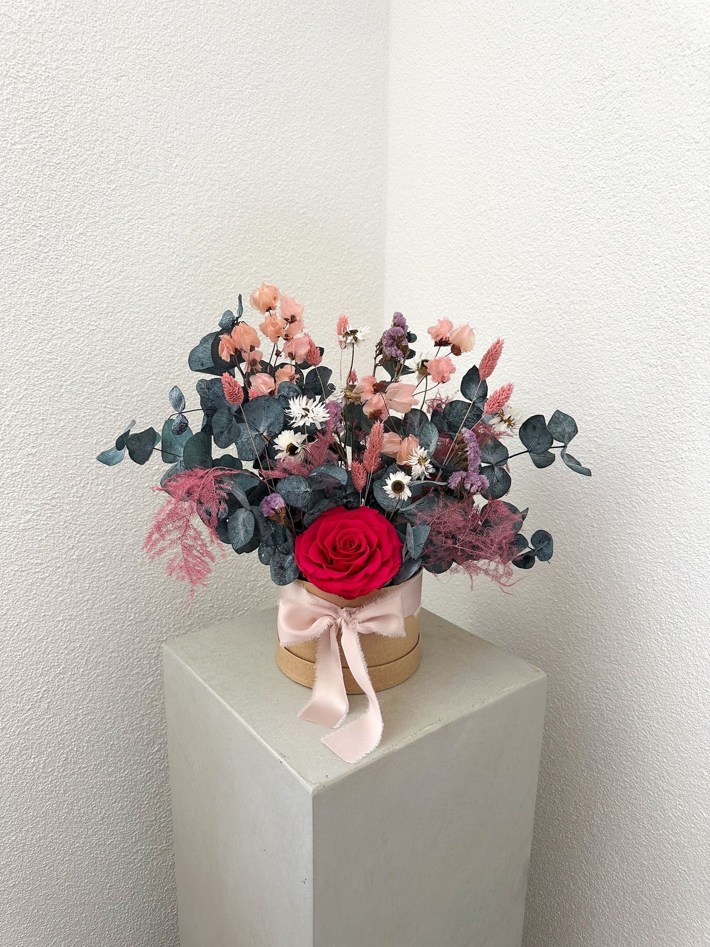 Trockenblumenbox „Lucia“ mit roter Rose, Eukalyptus, Limonium und Phalaris in eleganter Geschenkverpackung mit rosafarbener Schleife.