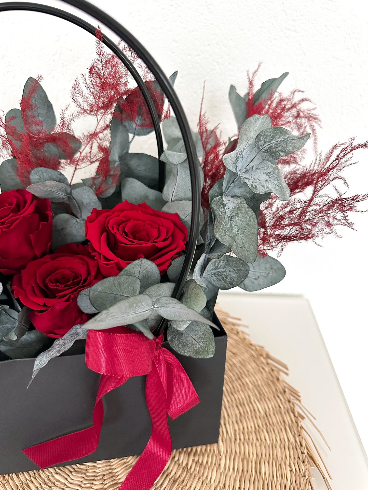 Gesamtansicht der luxuriösen Blumentasche mit stabilisierten Rosen, Eukalyptus und Farnen, arrangiert als stilvolle Dekoration.