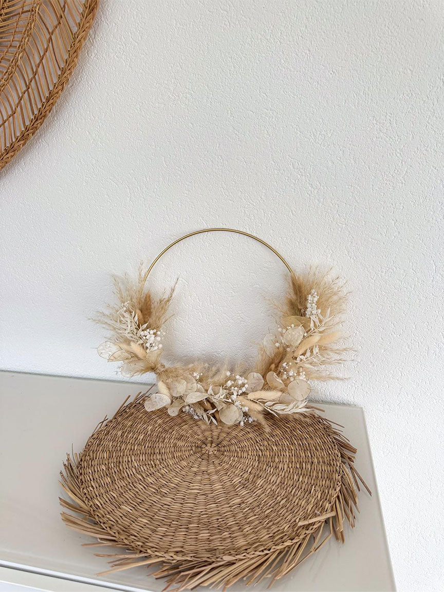 Handgefertigter Daniela Hoop mit einem Durchmesser von 30 cm, präsentiert auf einer hellen Wand. Die Kombination aus weichem Pampasgras, weißem Schleierkraut, flauschigem Lagurus und zartem Lunaria strahlt neben dem glänzenden Gold des Metallrings Natürlichkeit und Eleganz aus.