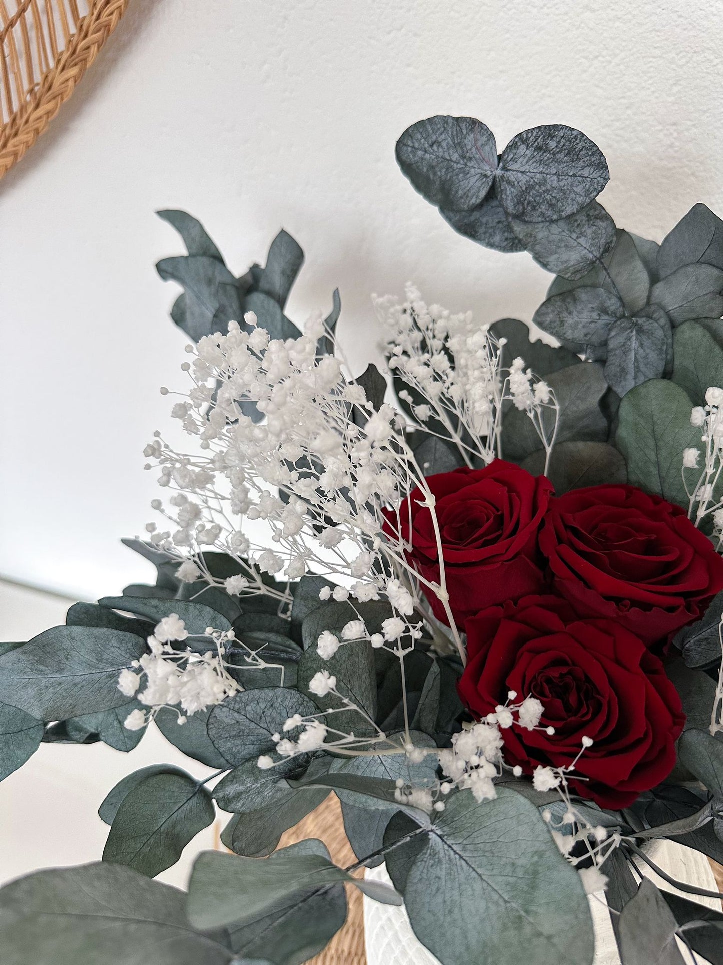 Nahaufnahme des Emina Bouquets mit drei roten Rosen, umgeben von Schleierkraut und Eukalyptus.
