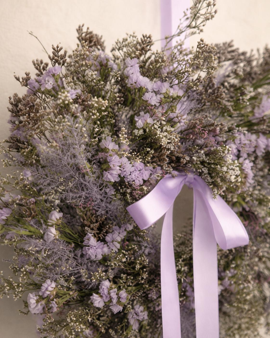 Detailansicht der Trockenblumen und fliederfarbenen Schleife von Kranz Melora