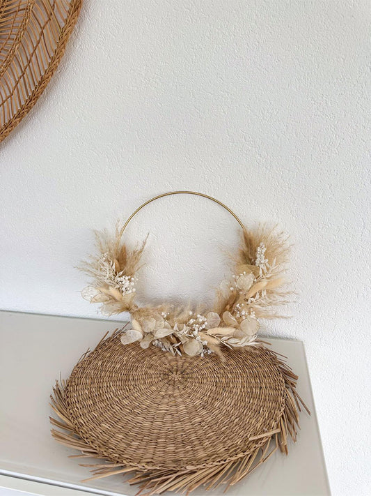 Handgefertigter Daniela Hoop mit einem Durchmesser von 30 cm, präsentiert auf einer hellen Wand. Die Kombination aus weichem Pampasgras, weißem Schleierkraut, flauschigem Lagurus und zartem Lunaria strahlt neben dem glänzenden Gold des Metallrings Natürlichkeit und Eleganz aus.