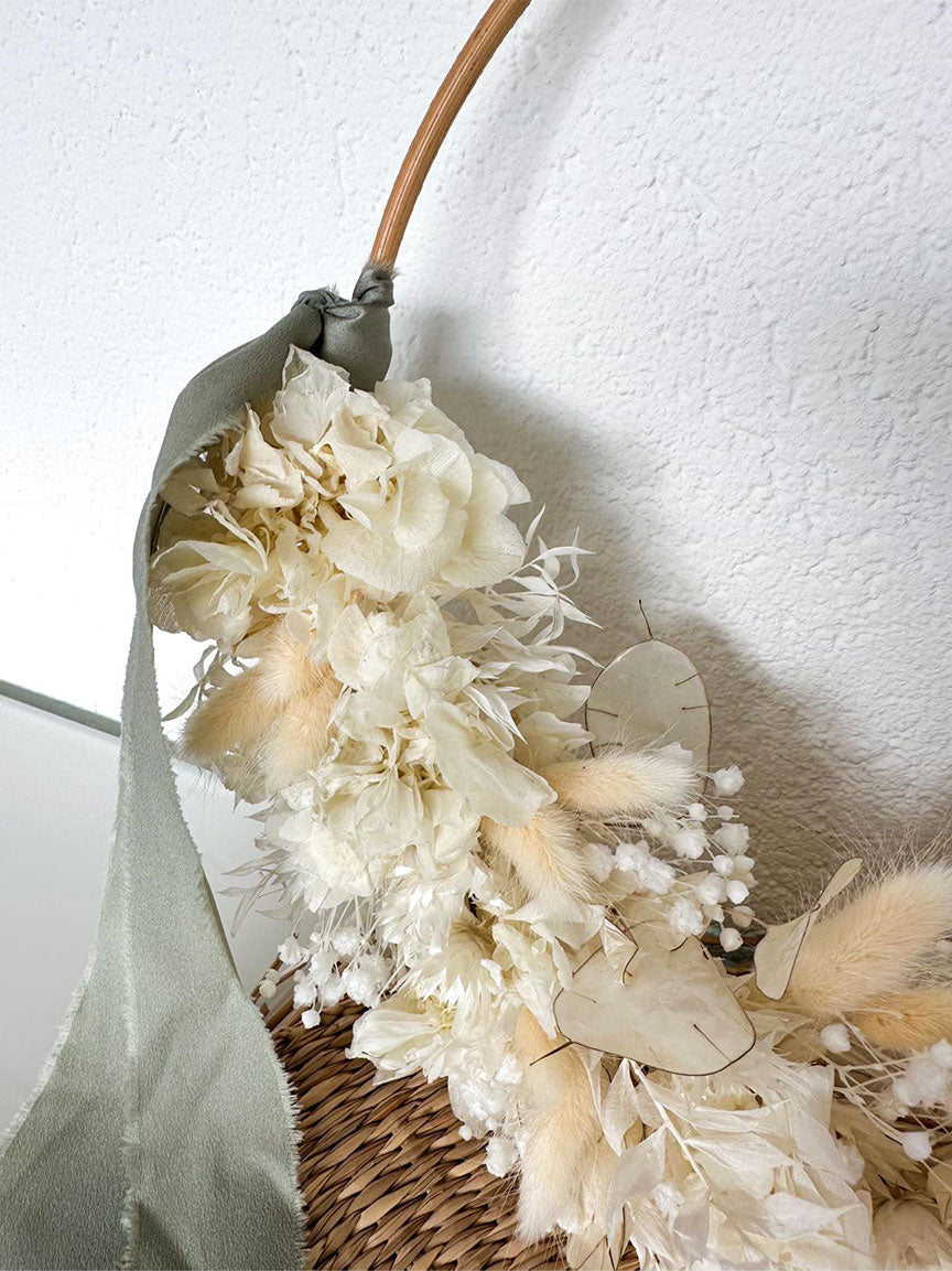 Detailansicht des Gloria Flowerhoops mit Hortensie, Lunaria und Schleierkraut auf einem Rattanhintergrund.