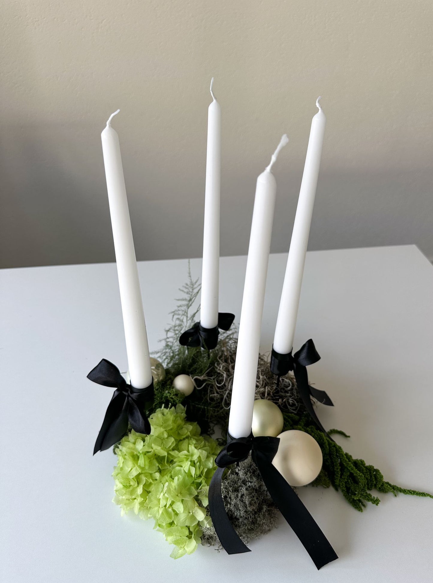 Seitliche Aufnahme des Adventskranzes Amire mit weissen Stabkerzen – Kombination aus Natur, Design und zeitloser Eleganz.