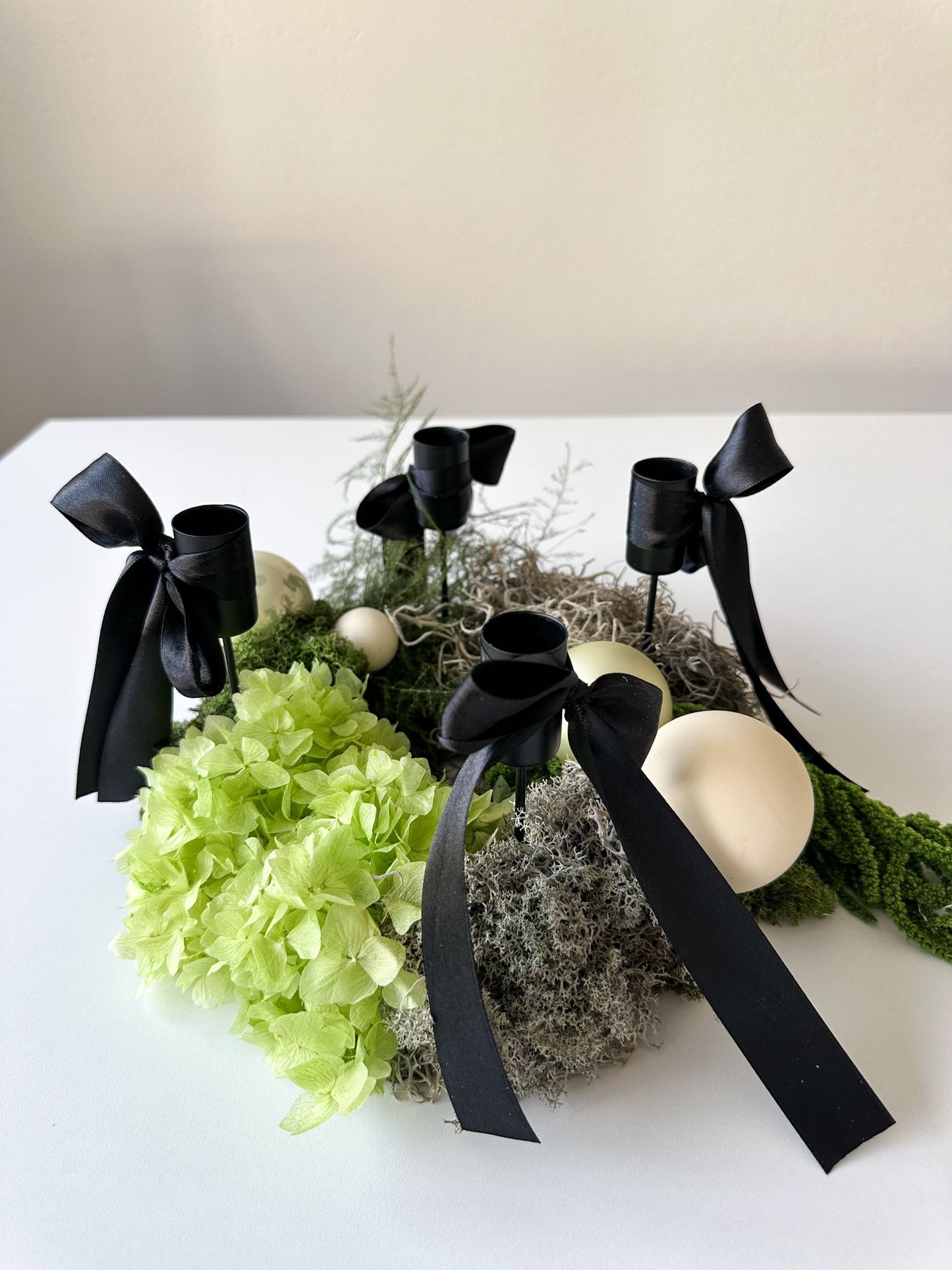 Adventskranz Amire von oben – Komposition aus Moos, Asparagus, Hortensie und Kugeldekoration in stilvollem Grün-Weiss-Schwarz.